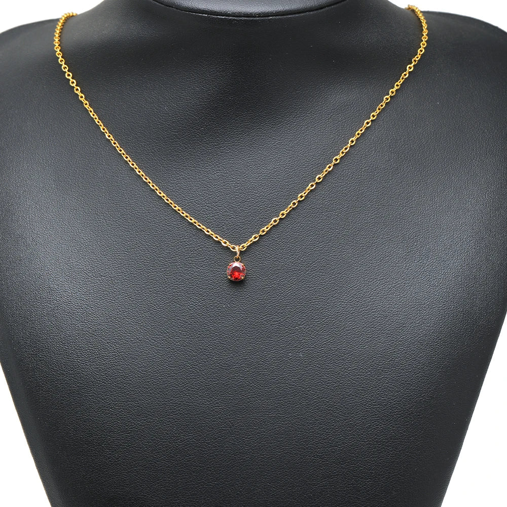 Gold chain necklace with a small round red crystal drop pendant