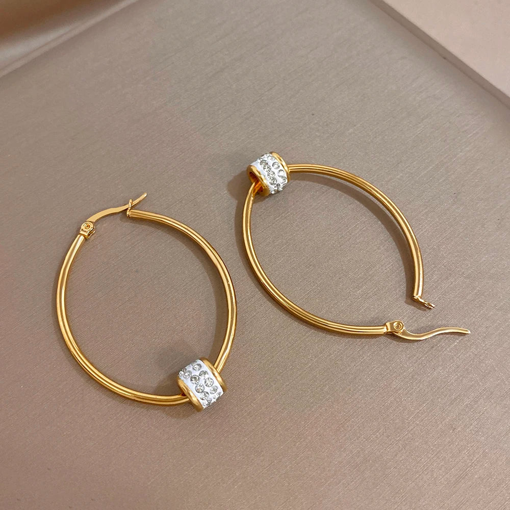 Gold-plated hoop earrings with clear rhinestone bead charm and hinge clasp detail