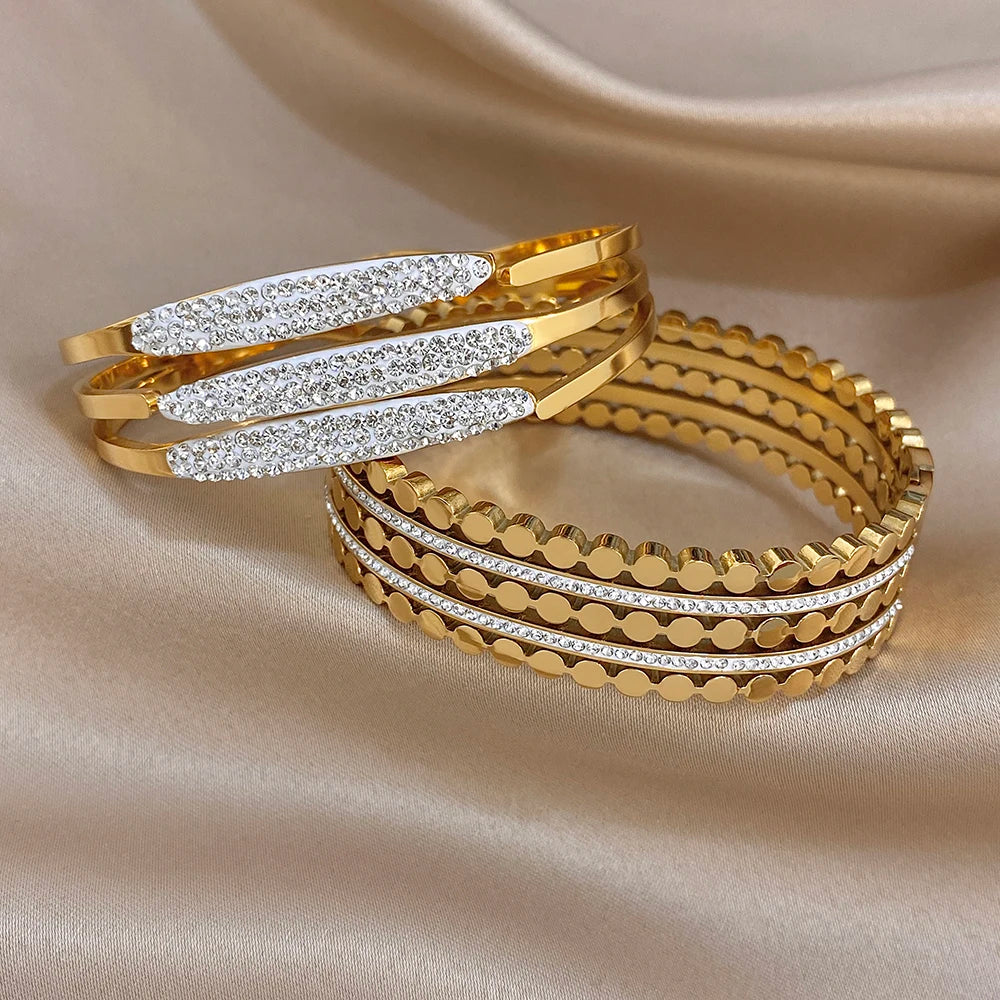 Gold-tone wide cuff bracelets with rhinestone bar inlays and textured circular link rims