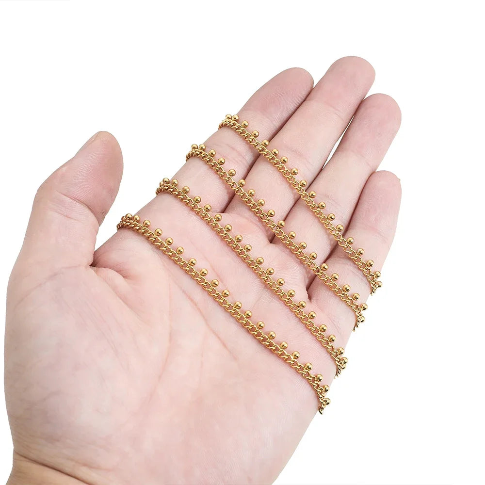 Gold beaded curb link chain set held in hand, showing small ball drop links