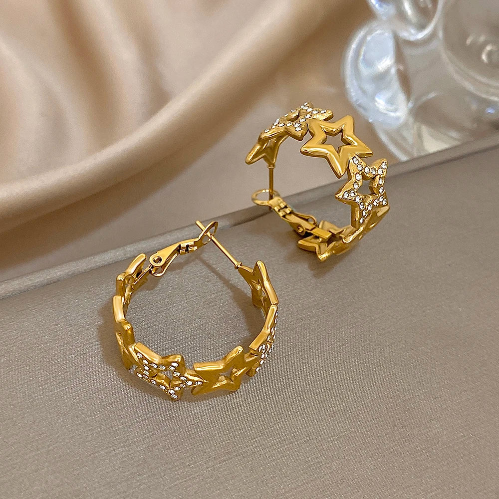 Gold-tone star hoop earrings shown open, with hinged posts and rhinestone accents