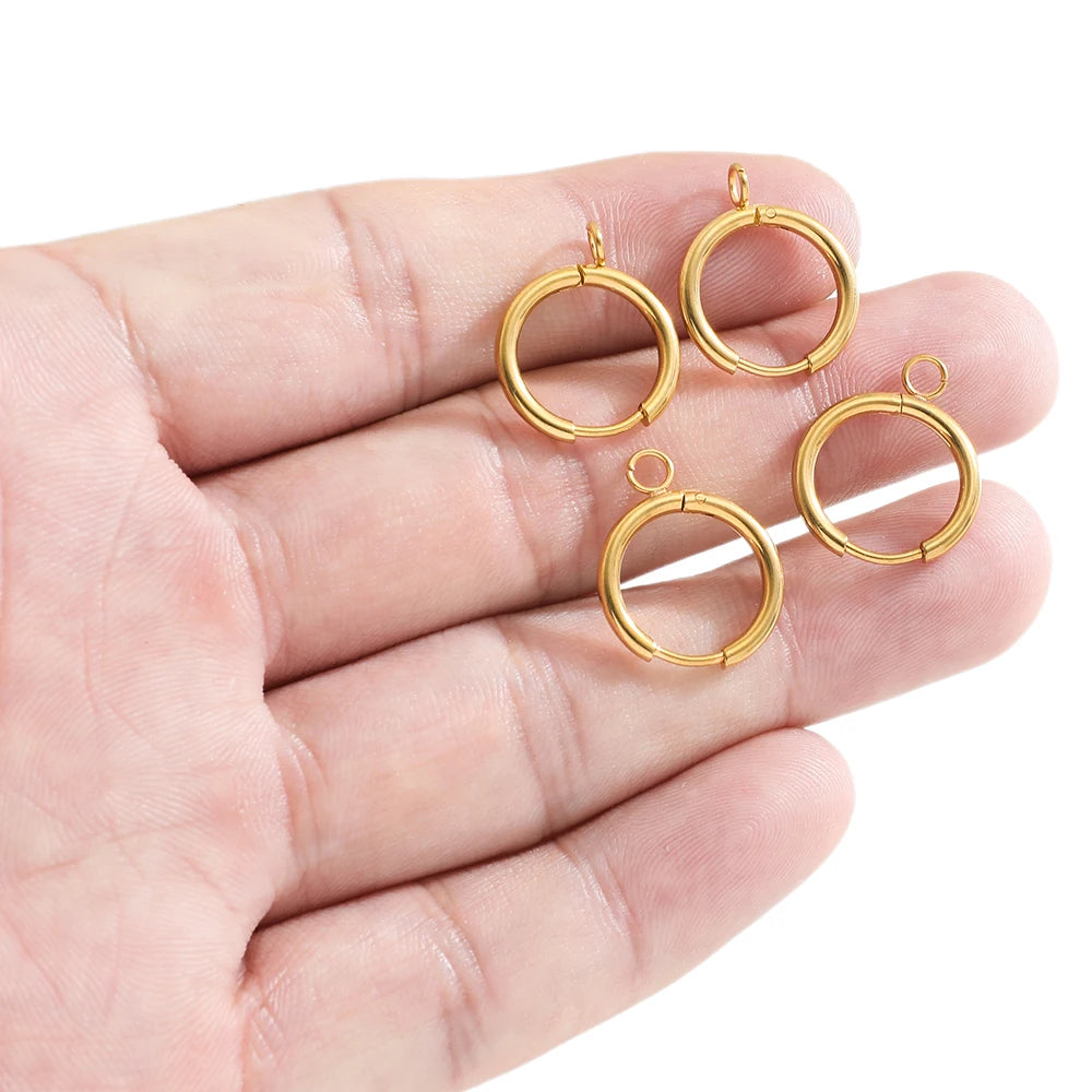 Gold-tone huggie hoop earring hooks with loop posts and jump rings in a hand.