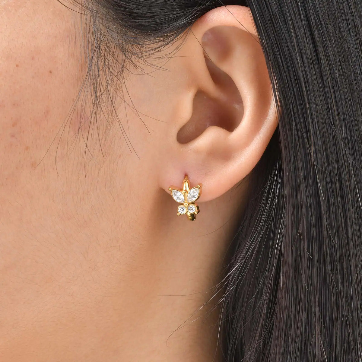 Gold-tone cubic zirconia flower stud huggie hoop earrings on ear