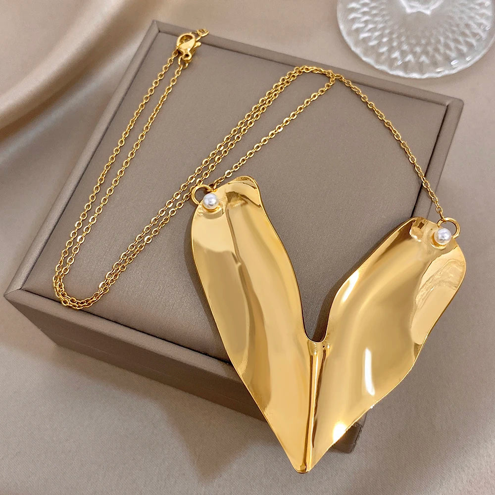 Gold-tone heart pendant necklace with pearl accents on a jewelry box display