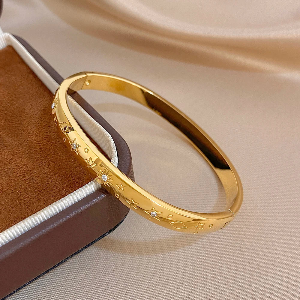 Gold-tone cuff bangle with star engravings and small crystal-like stones, side view