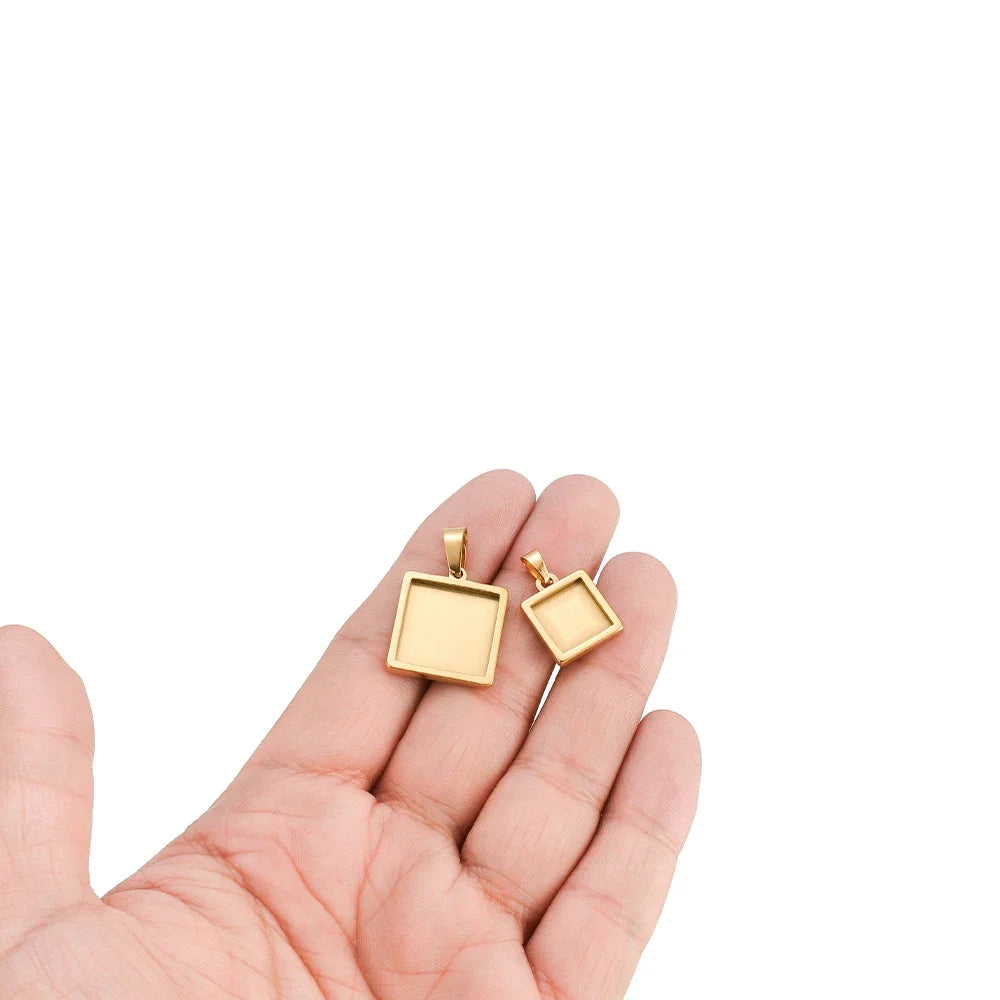 Square gold pendant tray bezels with bail, held in hand, cabochon blank charms set