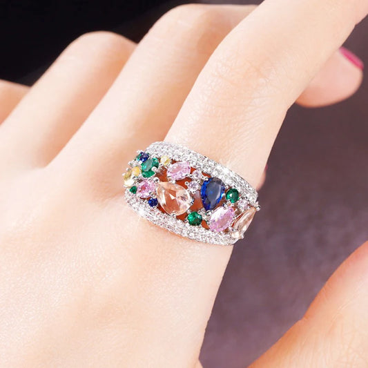 Silver-tone cubic zirconia ring with multicolor stones, shown on a hand close-up.