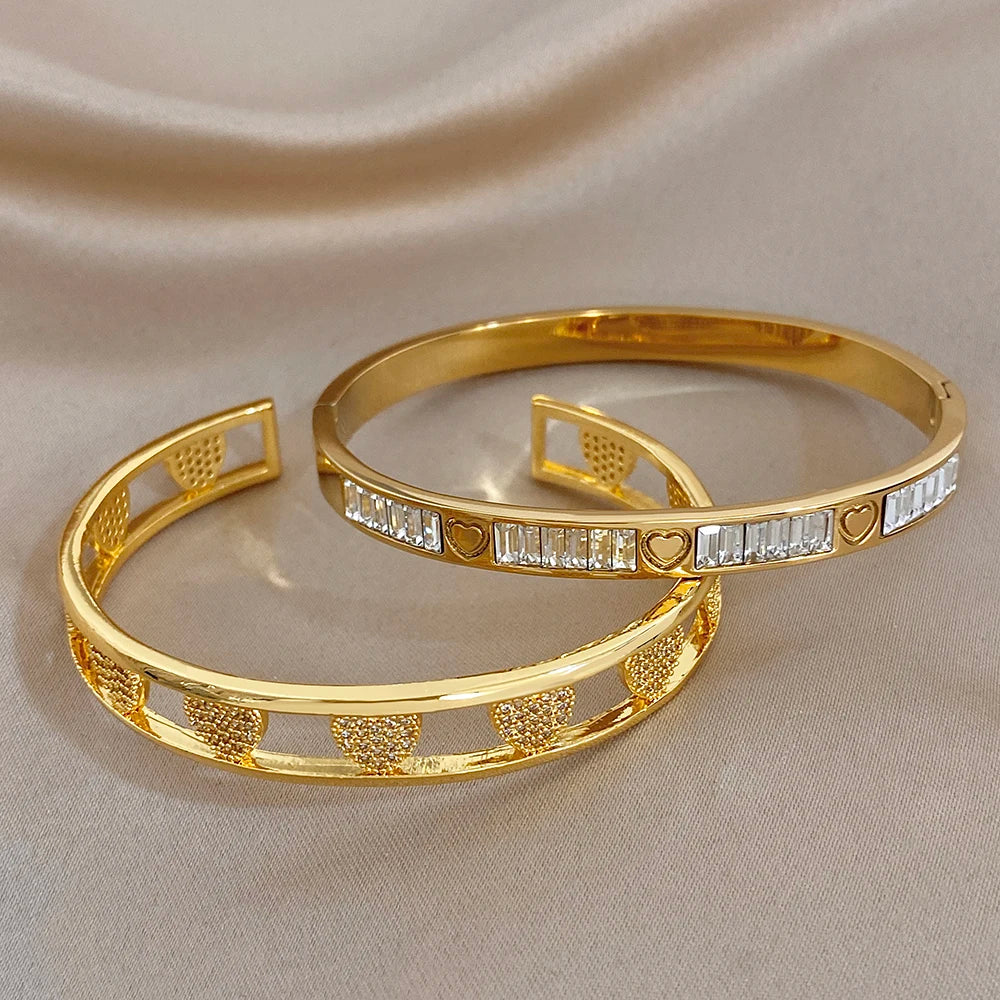 Pair of gold heart zirconia cuff bangles with clear stone insets and smooth finish