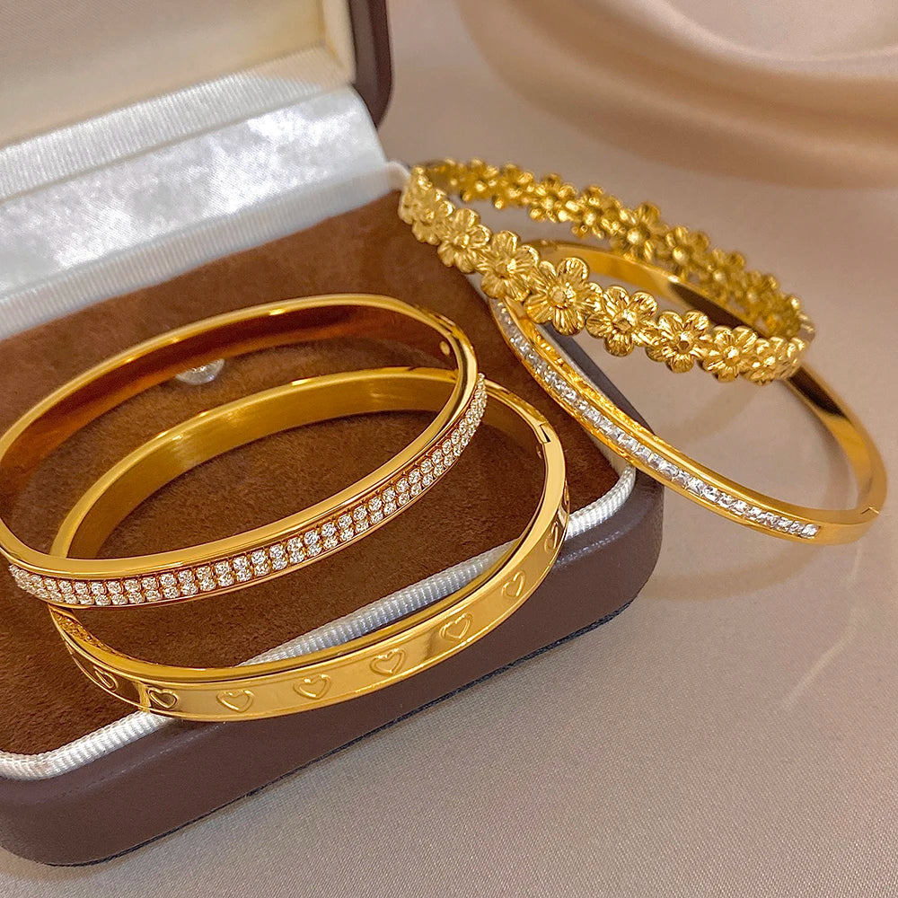 Gold tone bracelet bangles with rhinestone trim and raised floral heart texture