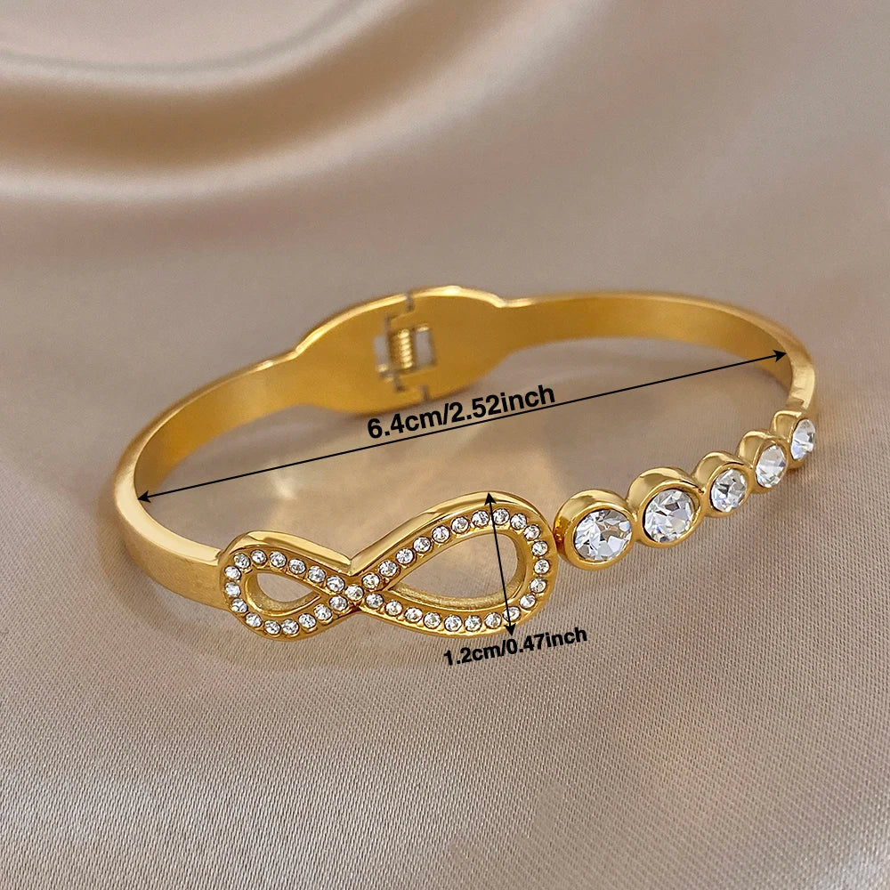 Gold-tone rhinestone infinity cuff bangle with round crystal stones and hinge closure