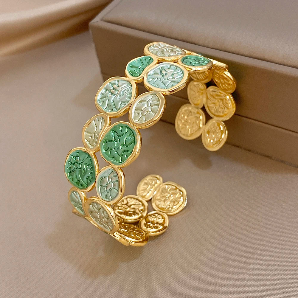 Gold-tone wide open cuff bracelet with green enamel leaf coin patchwork and gold charms