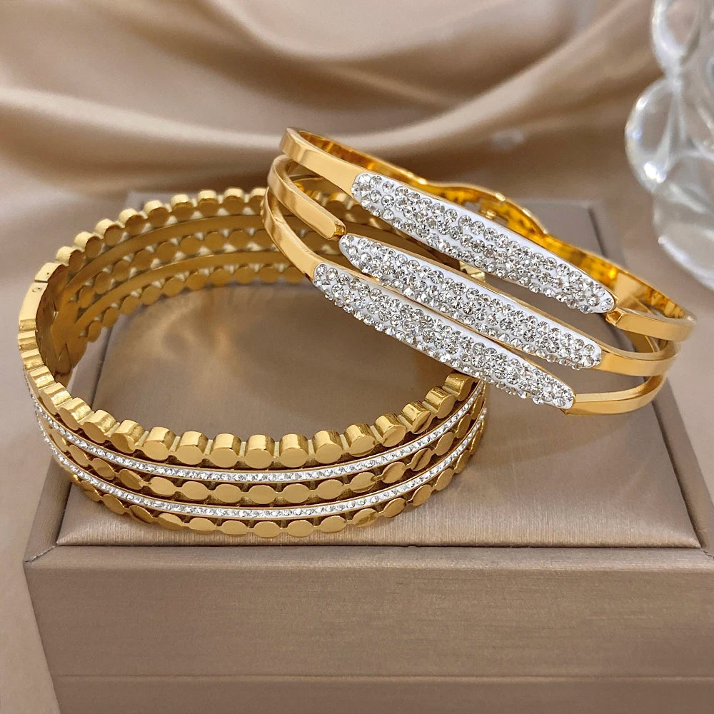 Gold-tone wide cuff bracelets set with sparkling rhinestone stripe panels and etched bands