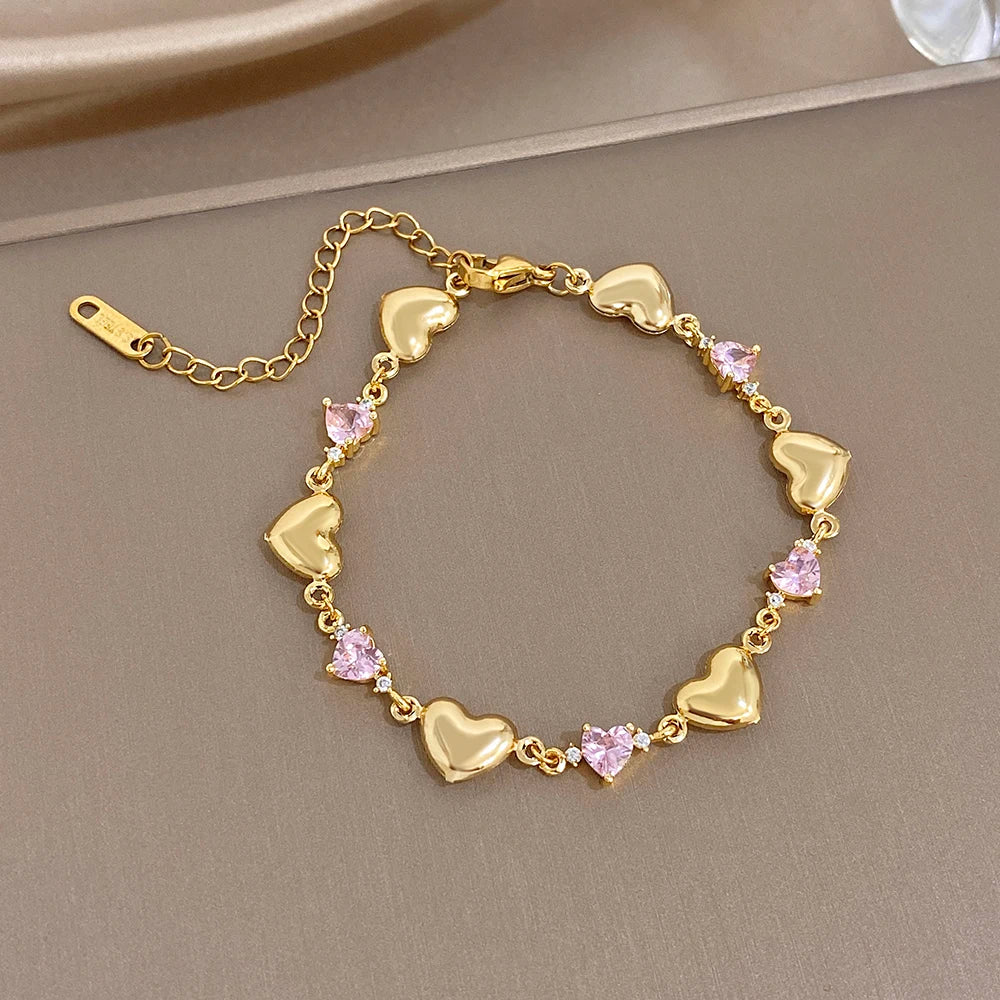 Gold-tone heart link bracelet with pink crystal-like stones along the chain