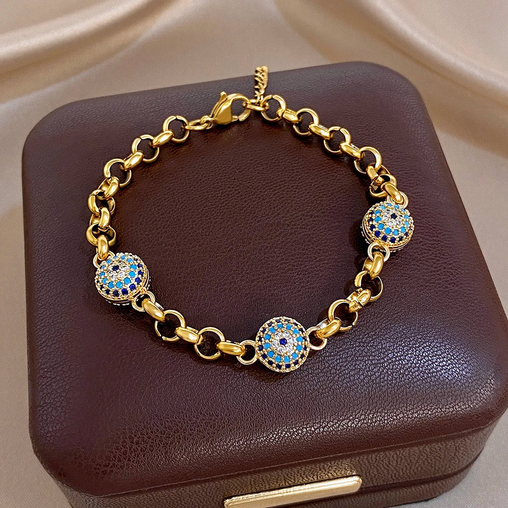 Gold-tone chain bracelet with blue evil-eye round charms on brown cushion