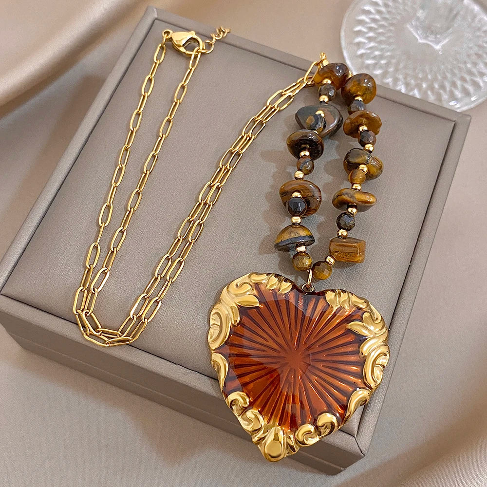 Heart pendant necklace in box with gold chain, brown bead strand, red sunburst heart charm