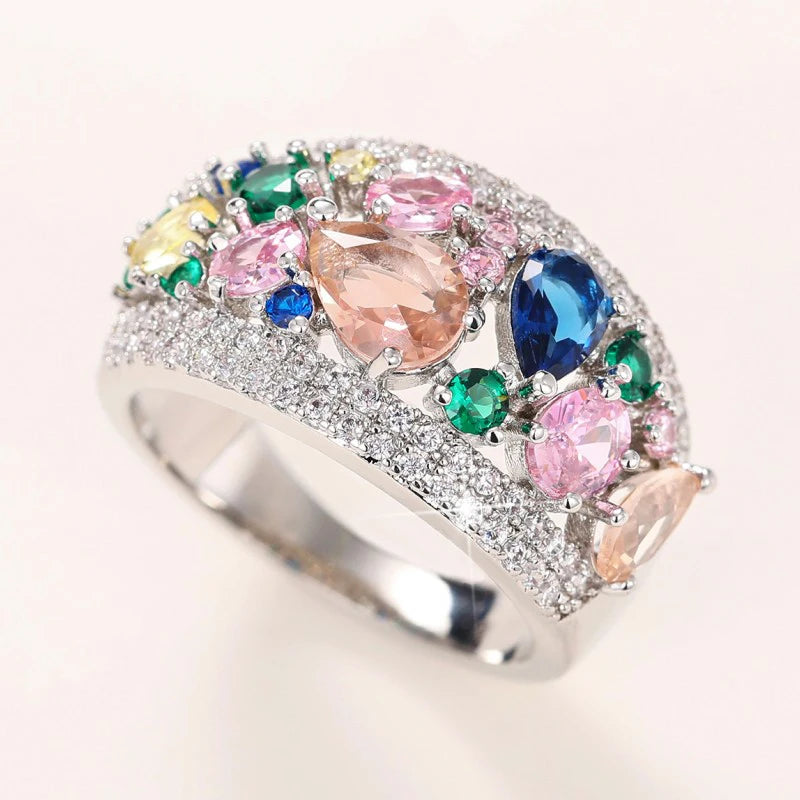 Silver-tone multi-stone cubic zirconia ring with pink and blue center stones, side view.