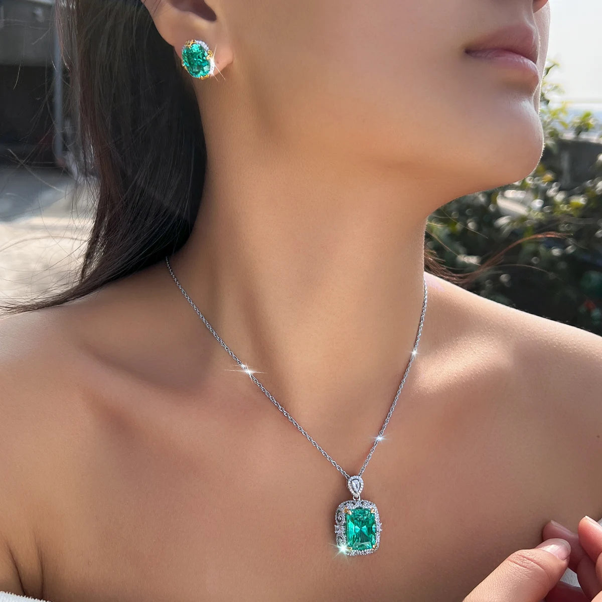 Green crystal pendant necklace and matching stud earring worn on a model
