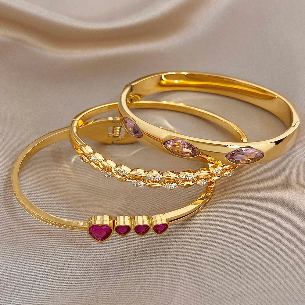 Set of gold tone stackable bangles with pink oval and purple heart zircon stones
