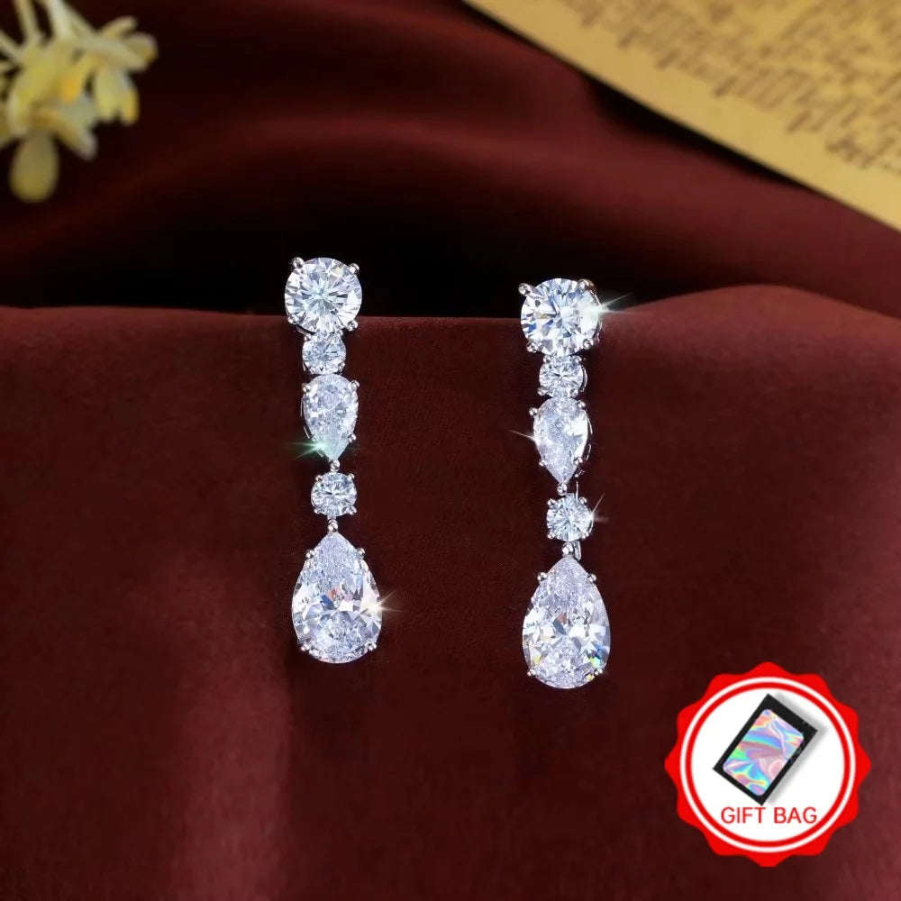 Cubic zirconia drop earrings with round and pear-shaped stones, paired with a gift bag.