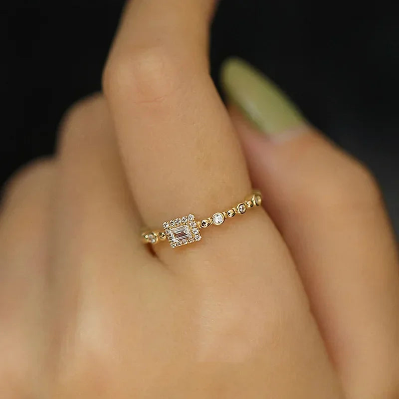 Gold-tone square-cut halo ring on finger with small round stones along band