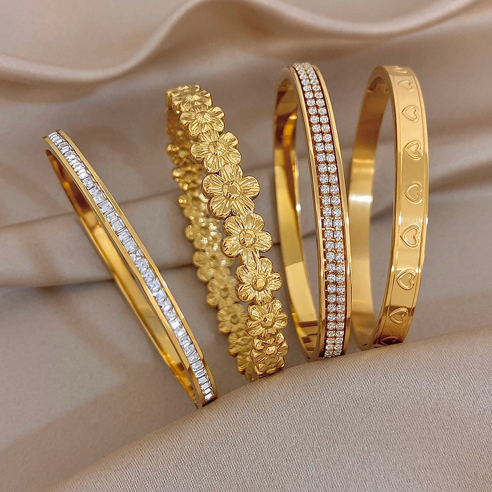 Gold tone cuff bangles set with rhinestone strip and floral heart-style carvings