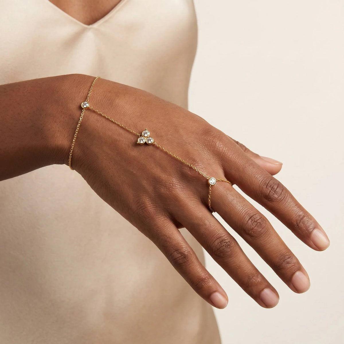 Gold-tone hand chain bracelet with three CZ heart motifs along chain