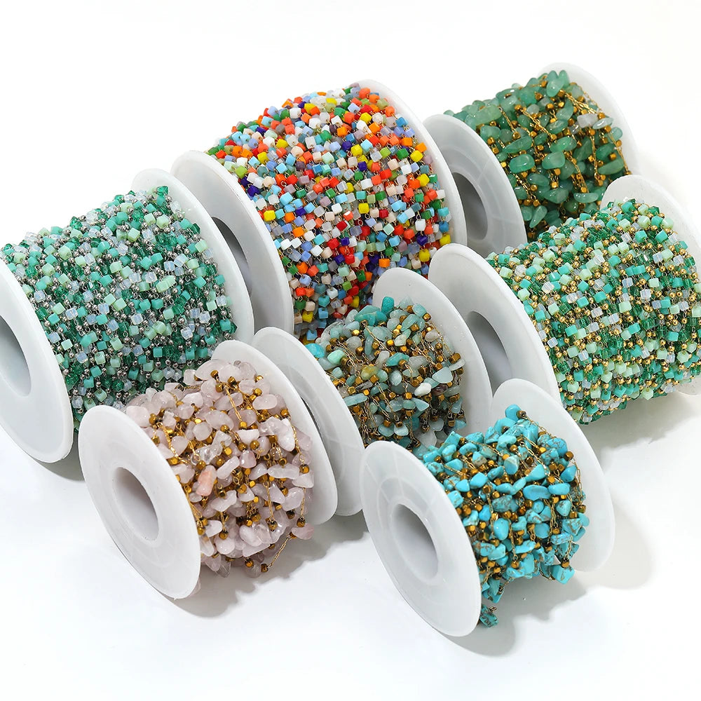 Assorted irregular glass bead link chain rolls on white spools, teal, orange and green tones