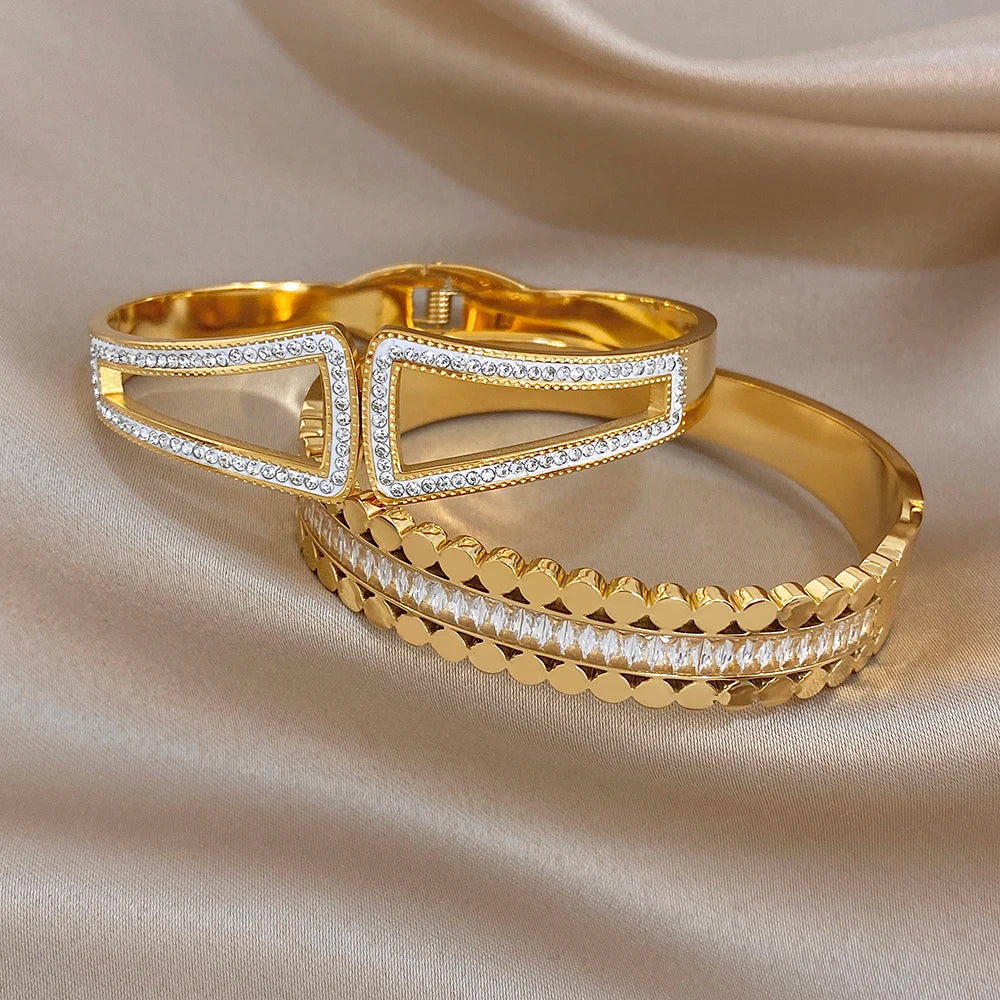 Gold-tone cuff bangle pairs with openwork geometric motif and rhinestone border