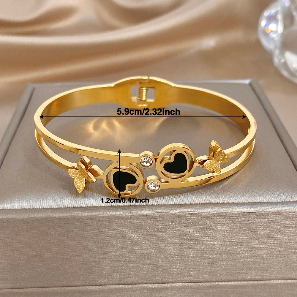 Gold-tone heart-circle cuff bangle with black enamel, butterflies, and clear crystal stones