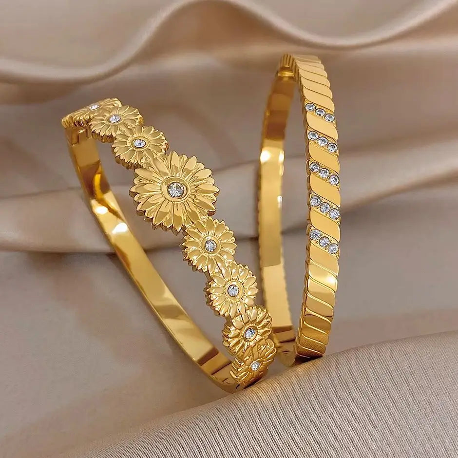 Gold tone cuff bangle with embossed flower medallions and clear rhinestone accents