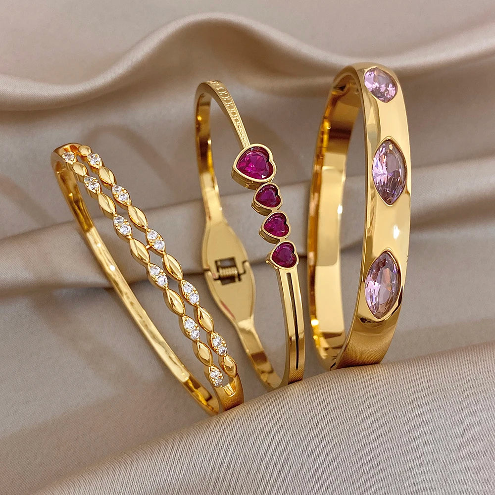 Gold tone stackable bangles with pink heart and oval zircon stones, curved cuffs