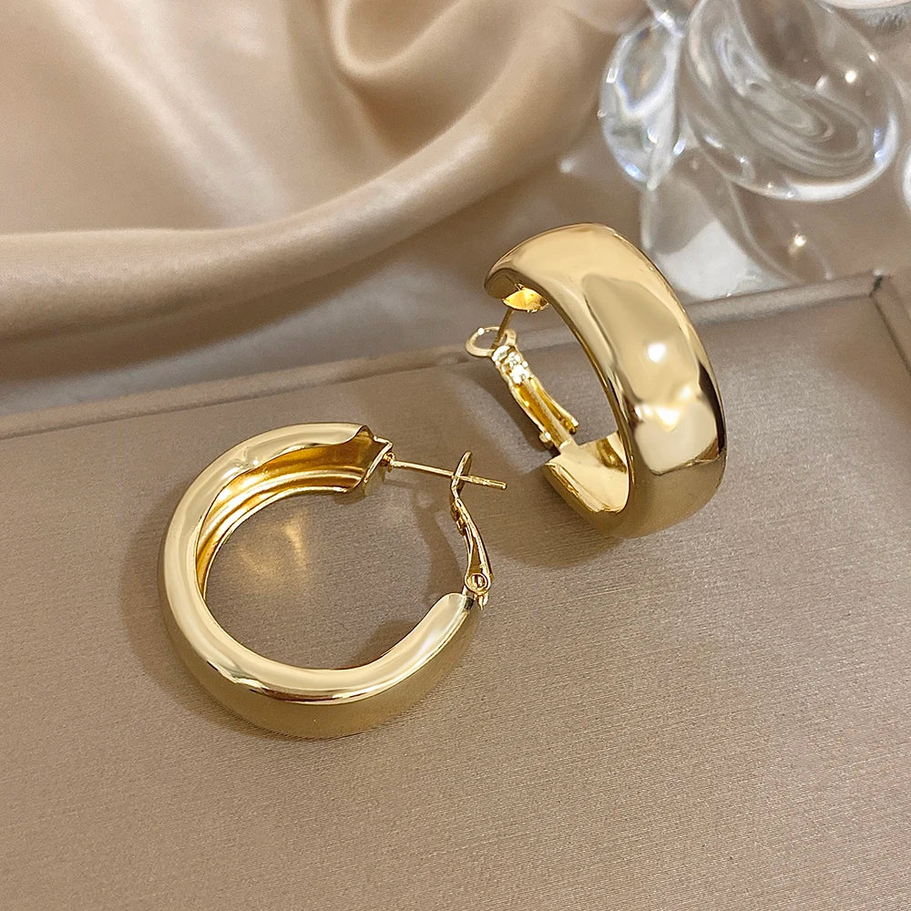 Gold-tone chunky hoop earrings with hinged clasp and polished finish
