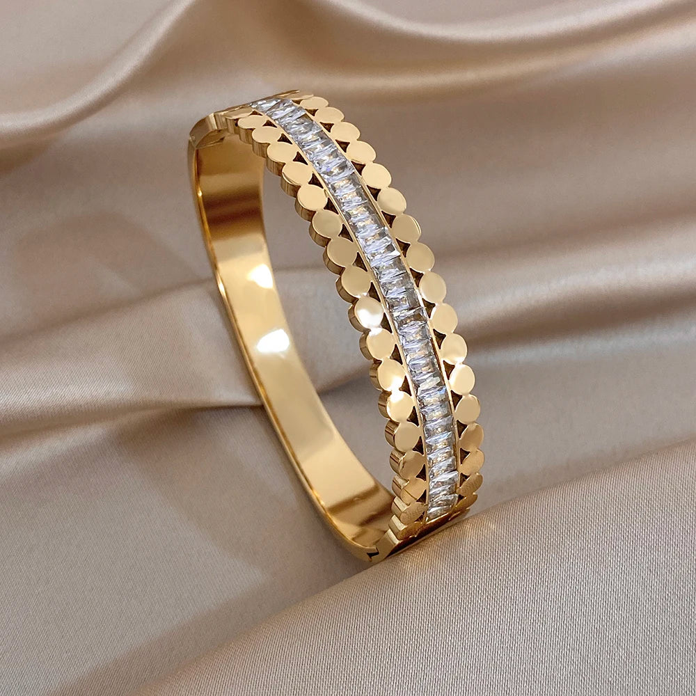 Gold-tone cuff bangle with stacked bead texture and clear rhinestone side band