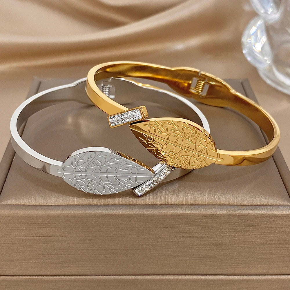 Gold and silver leaf-pattern cuff bangles with rhinestone bar accents and clasp.