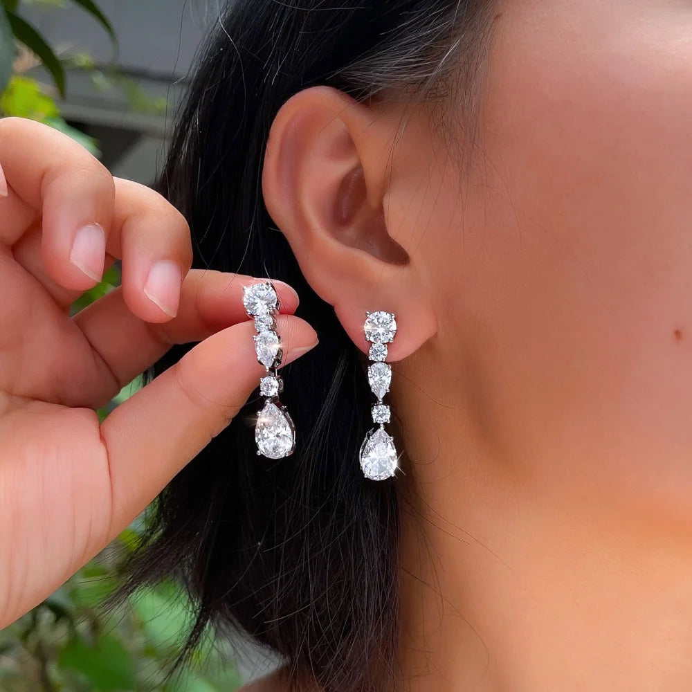 Long cubic zirconia drop earrings with round and pear-shaped stones, shown worn.
