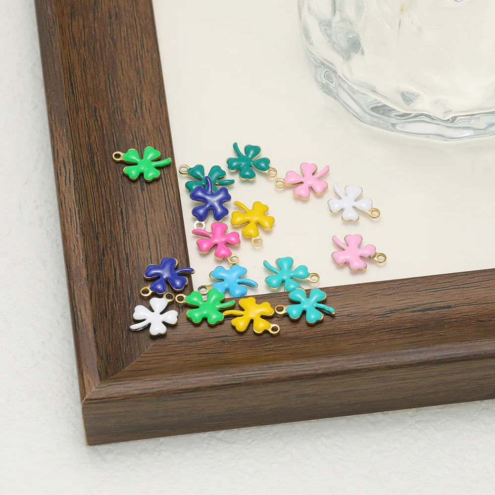 Colorful enamel clover charms with gold-tone loops, scattered near frame edge