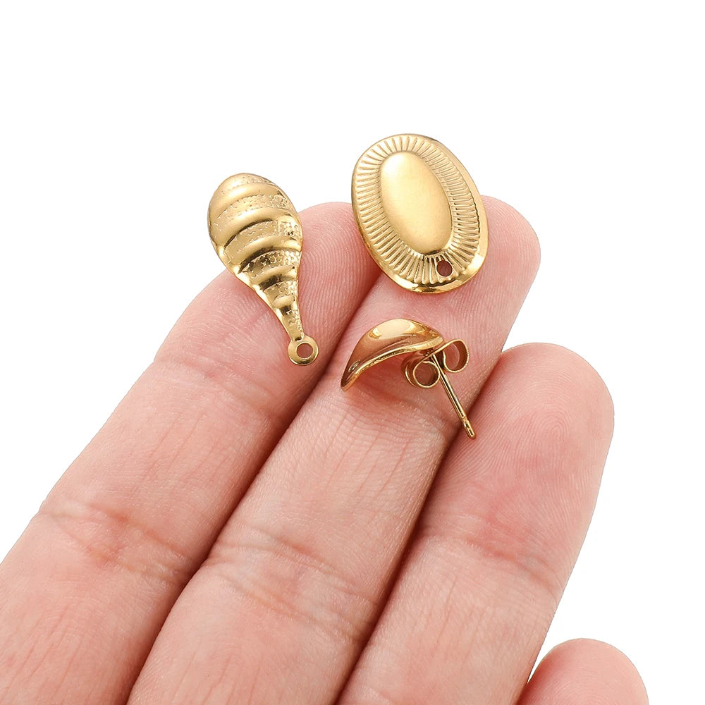 Gold oval stud earring findings in fingers, with connector loops and back posts