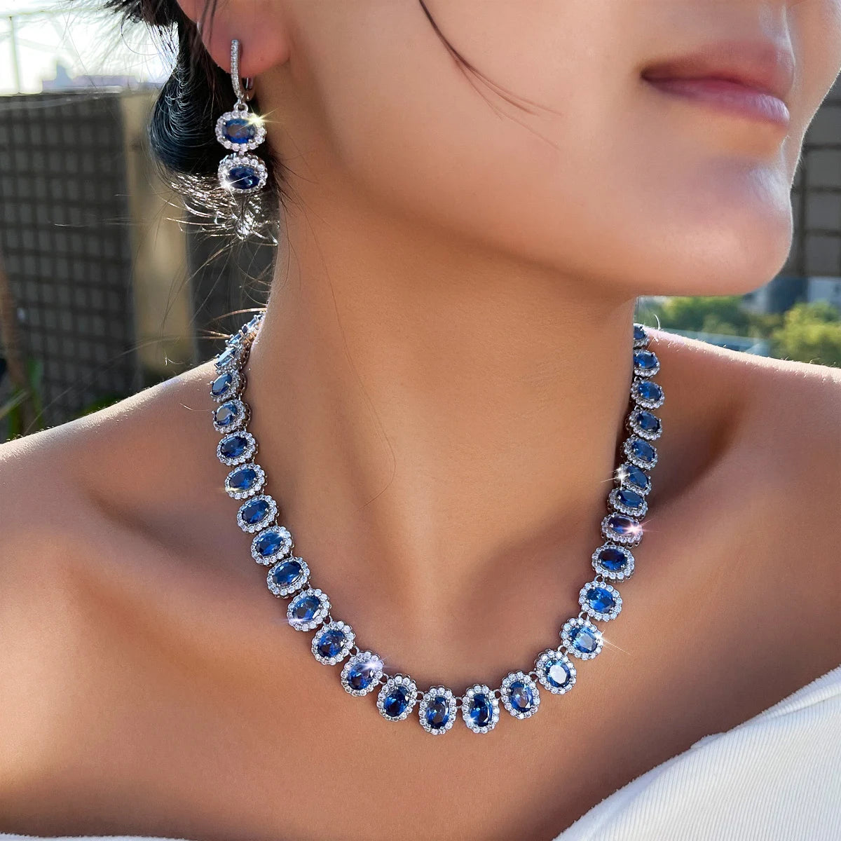 Royal blue cubic zirconia necklace with drop hoop earrings, close-up on model