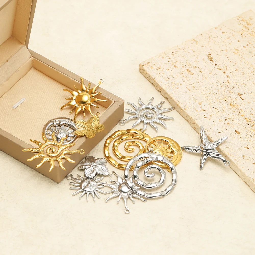 Gold and silver-tone sun and starfish charms arranged on a gift box and tiles