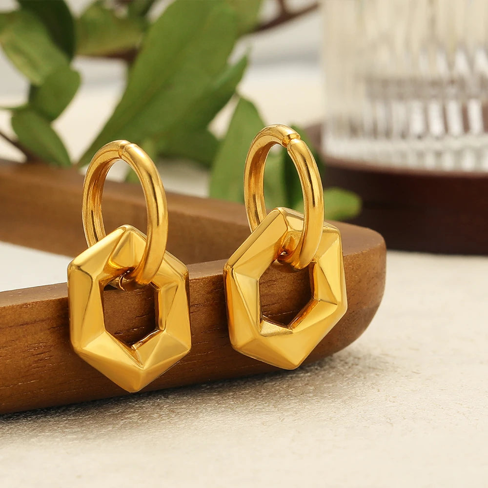 Close-up of two gold U-shaped stainless steel charms with faceted hexagon details