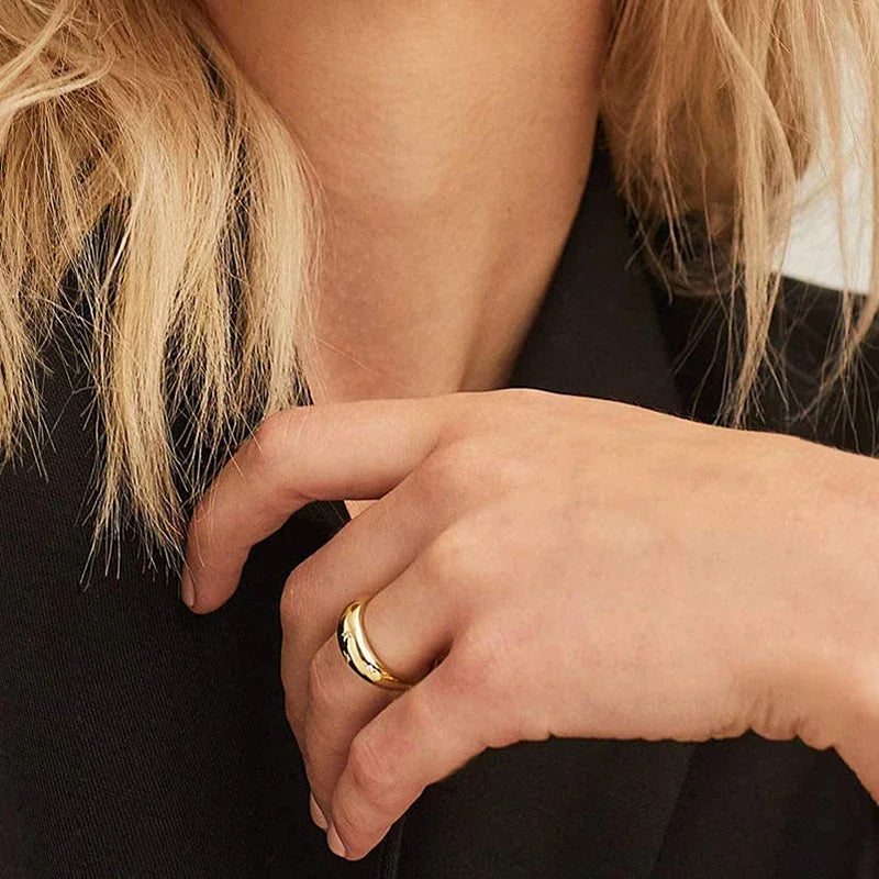 Gold-tone star wedding band on finger, hands clasped near collar area