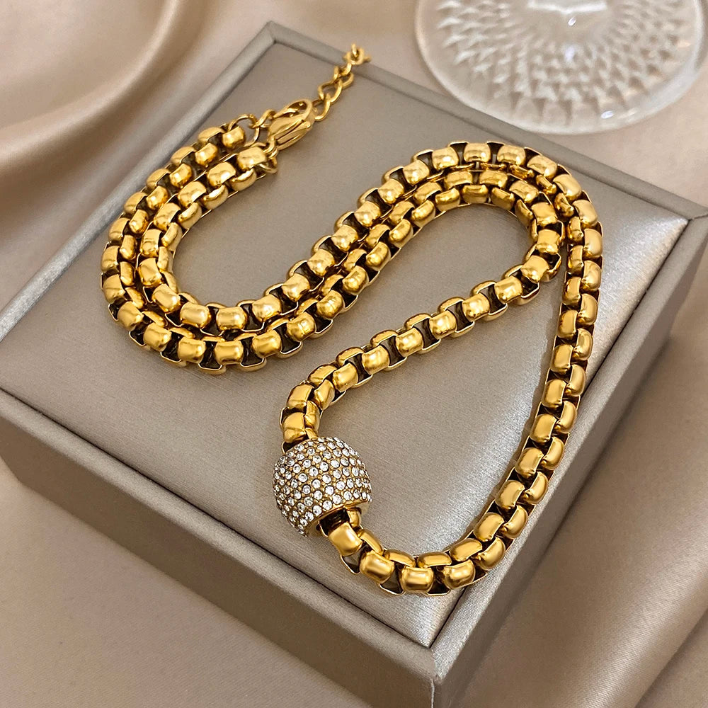 Gold-tone chunky chain choker with round rhinestone center bead on display tray