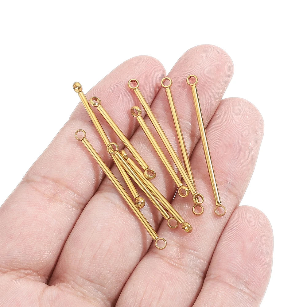 Gold stainless steel double-cylinder rod earring connectors held in palm, loop eyelets visible