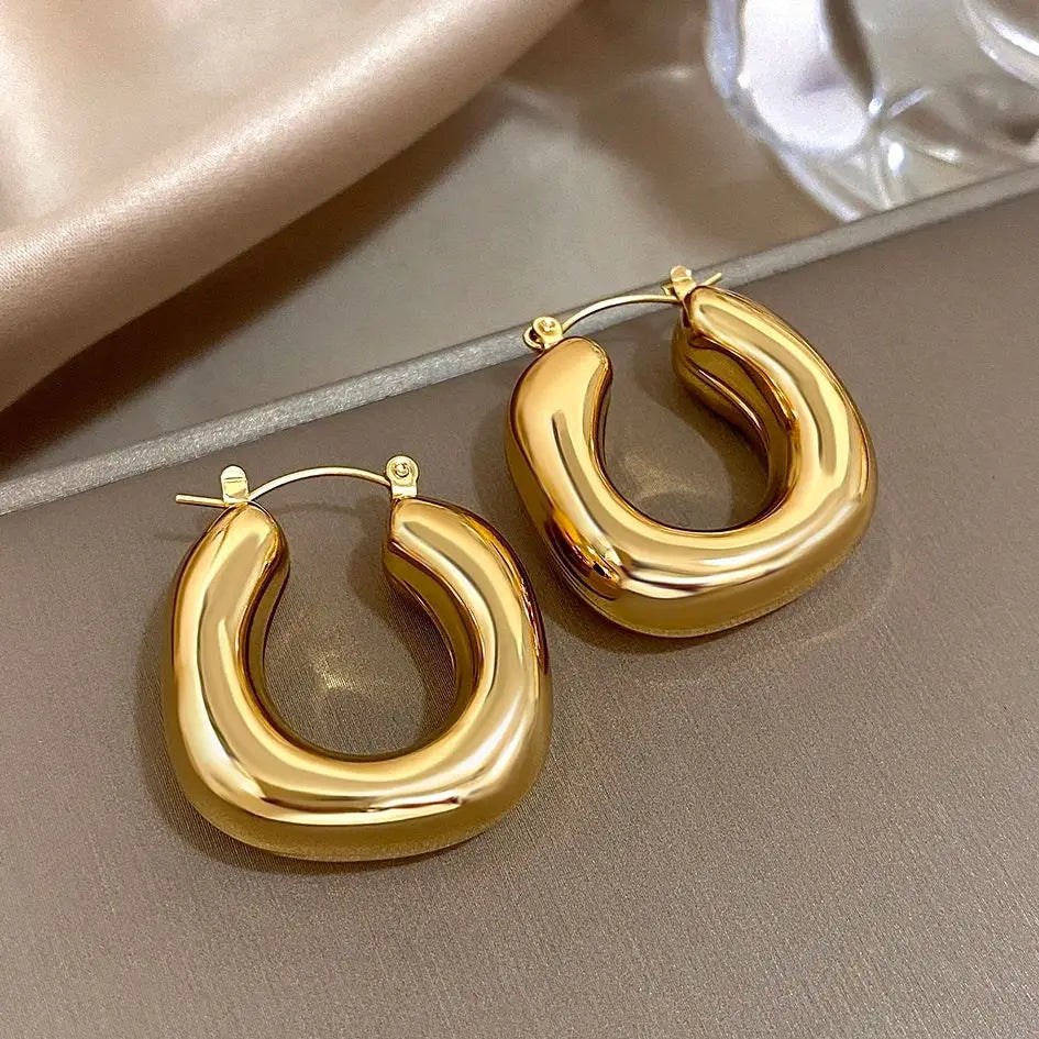 Pair of chunky gold-tone U-shaped hoop earrings with smooth, rounded surfaces