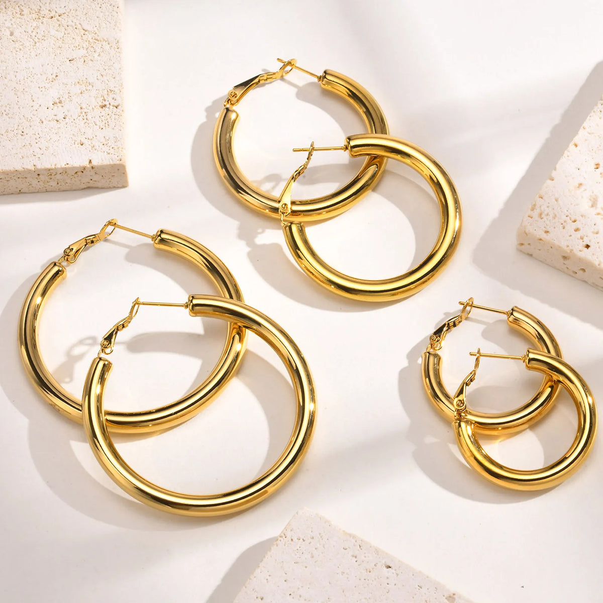Gold chunky hoop earrings in three sizes with hinged clasps