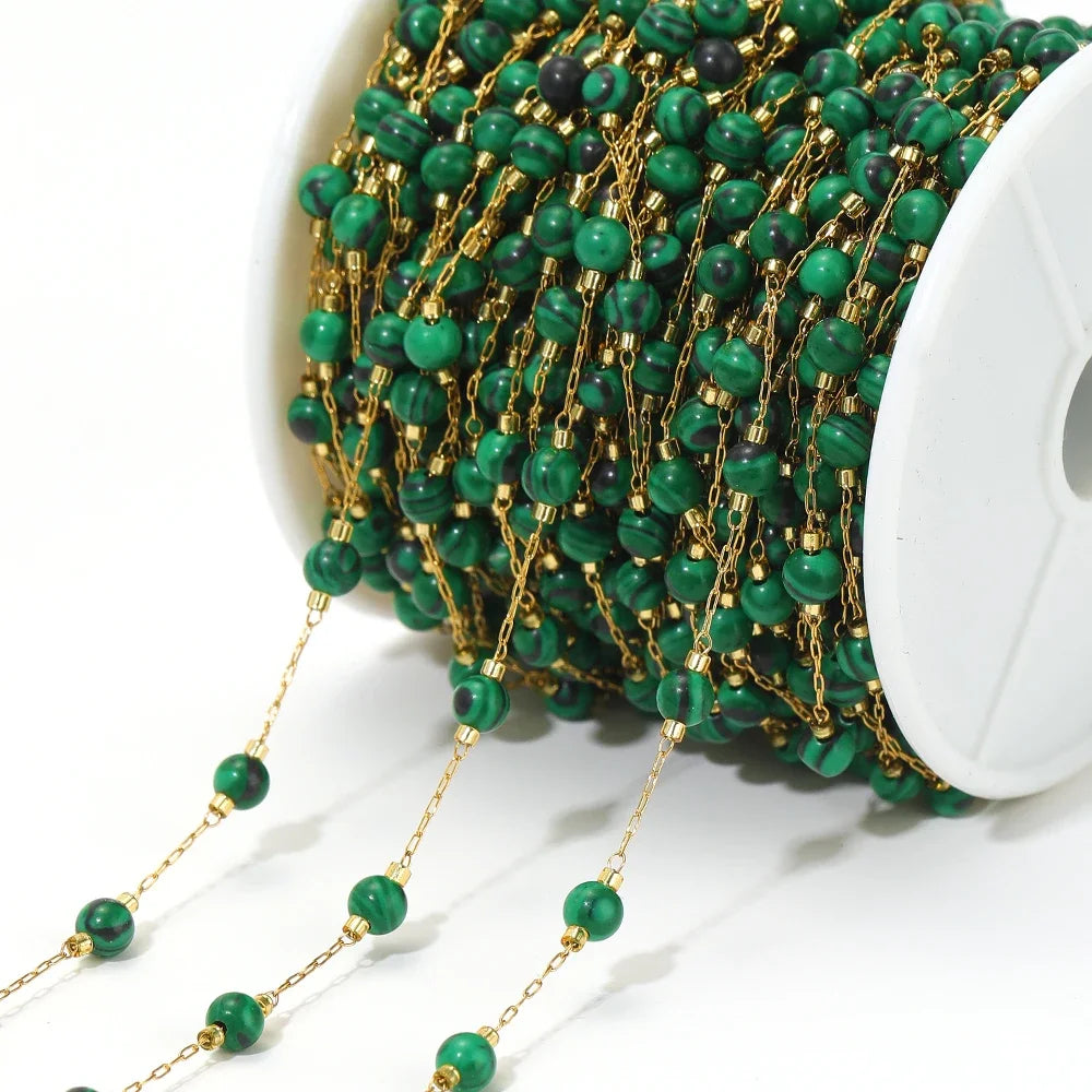 Green bead chain with gold-tone links and round turquoise beads on a white spool