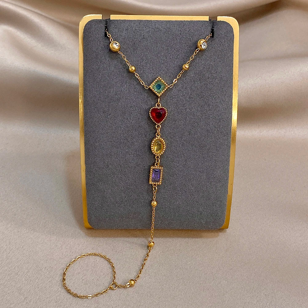 Gold-tone charm bracelet with red, blue, green and purple heart gemstone links