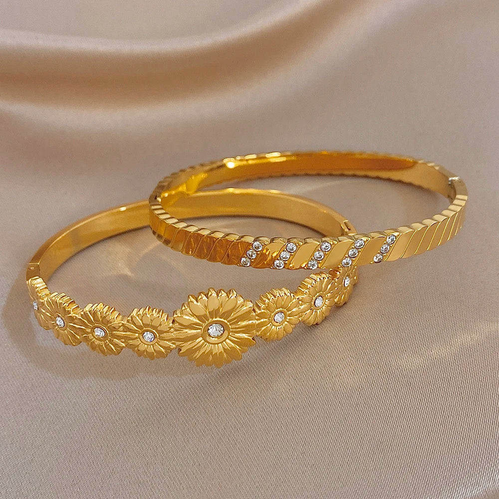 Gold tone stackable bangles with floral medallions and clear rhinestone stripe