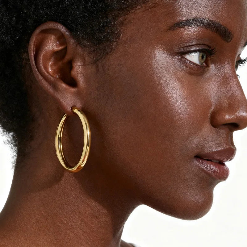 Gold chunky hoop earring worn on an ear
