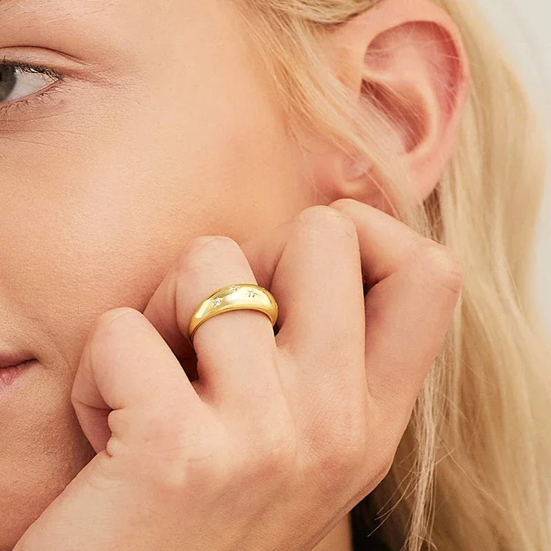 Gold-tone star wedding band on finger, woman close-up touching near ear